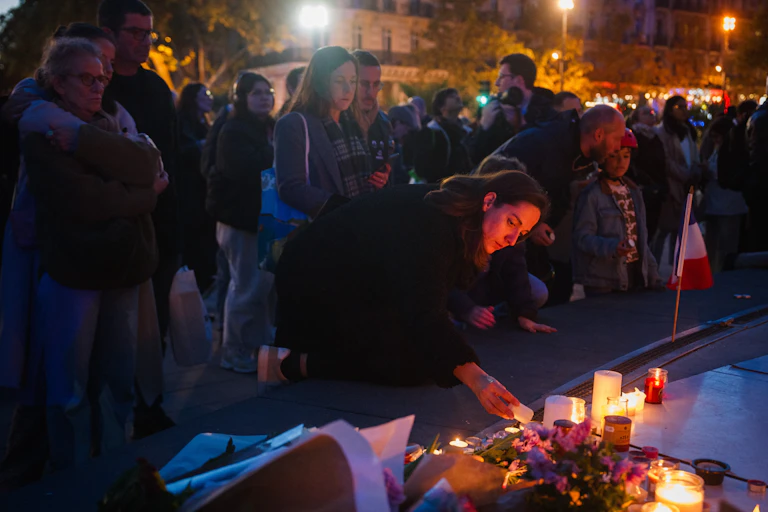 Une femme allume une bougie devant un mémorial improvisé en hommage aux victimes des attentats du 13 novembre 2015, place de la République, à Paris, le 11 novembre 2025.