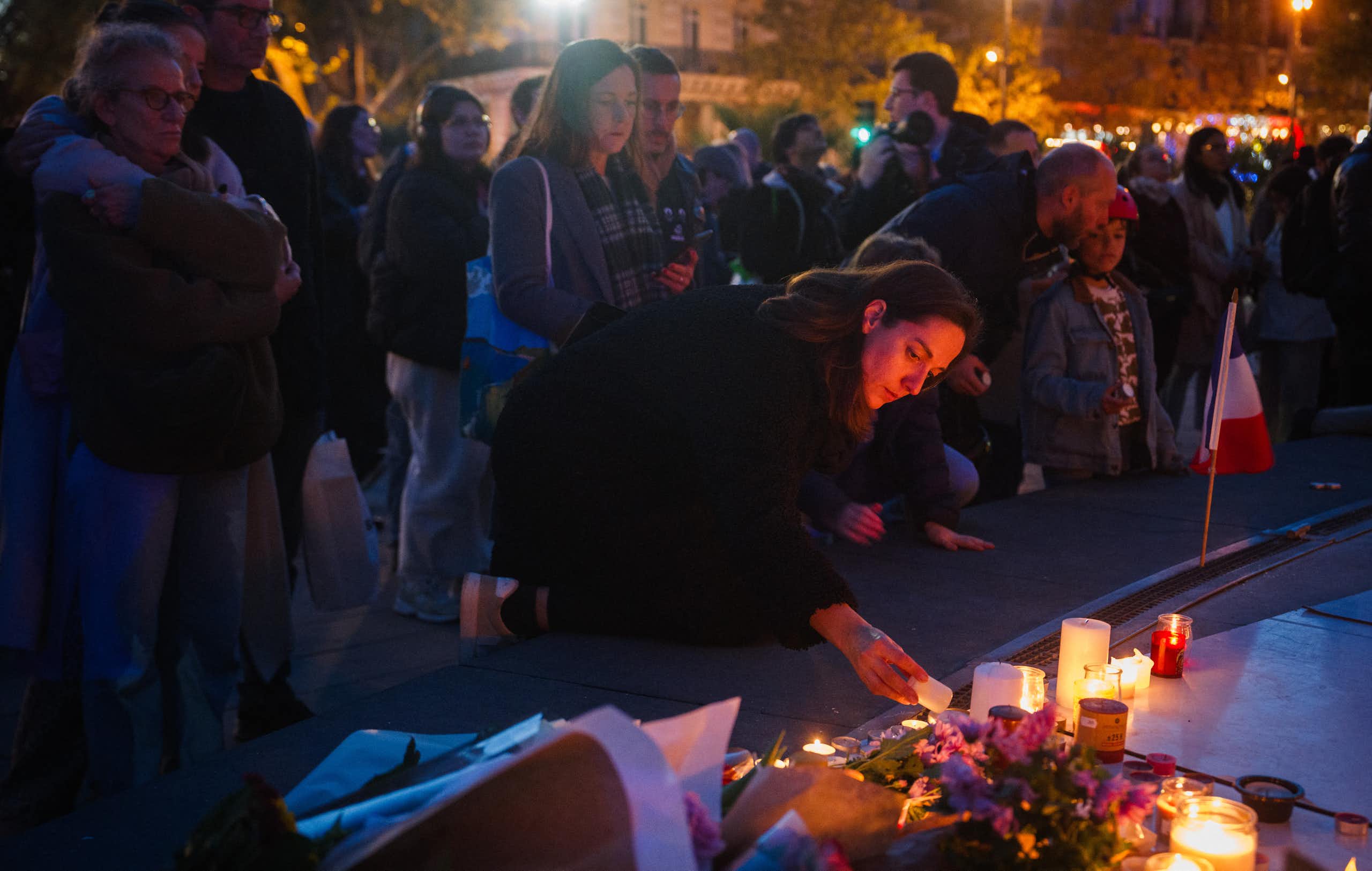 Une femme allume une bougie devant un mémorial improvisé en hommage aux victimes des attentats du 13 novembre 2015, place de la République, à Paris, le 11 novembre 2025.