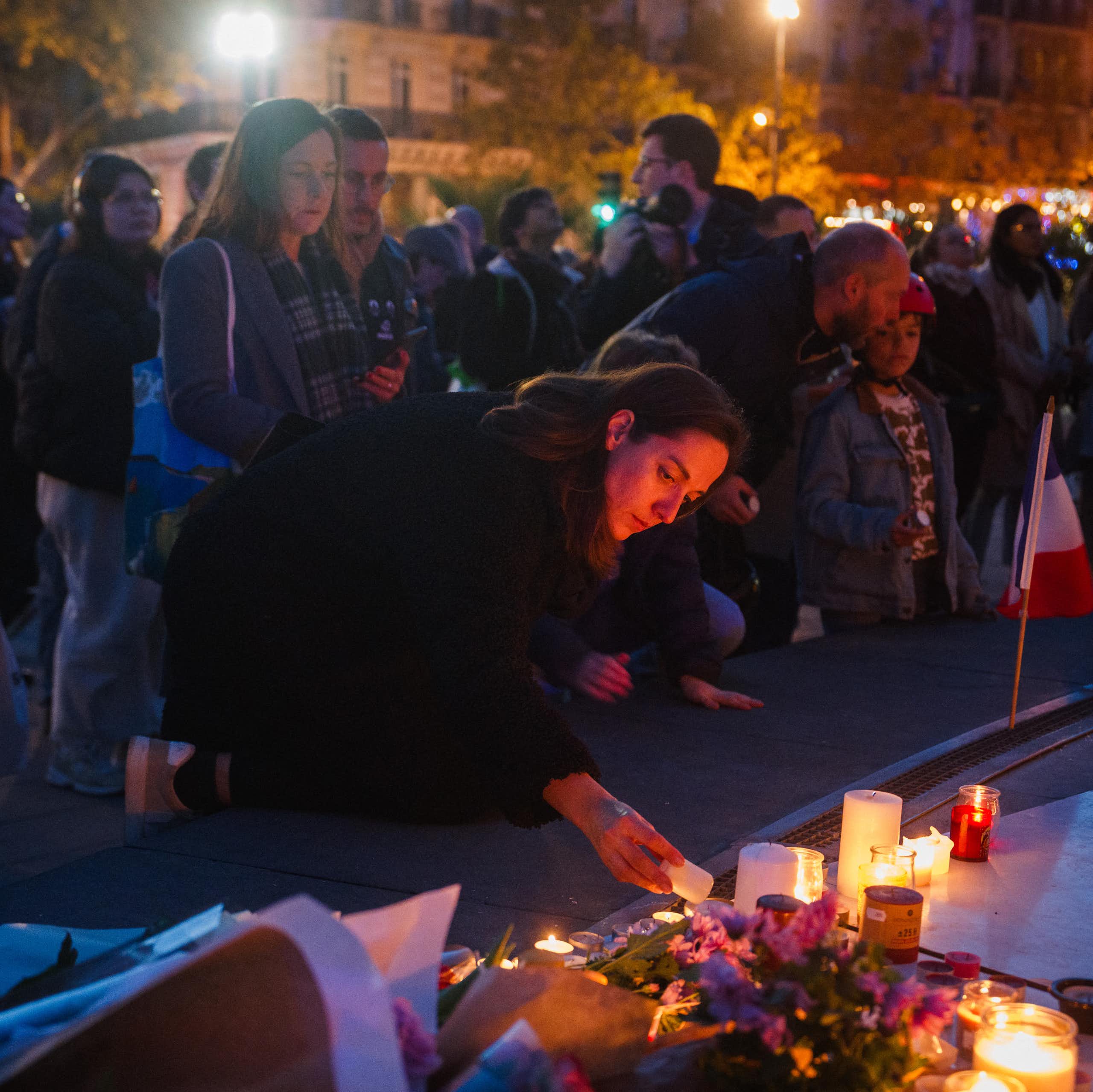 Une femme allume une bougie devant un mémorial improvisé en hommage aux victimes des attentats du 13 novembre 2015, place de la République, à Paris, le 11 novembre 2025.