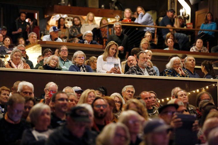 A group of people in a meeting listen to someone.
