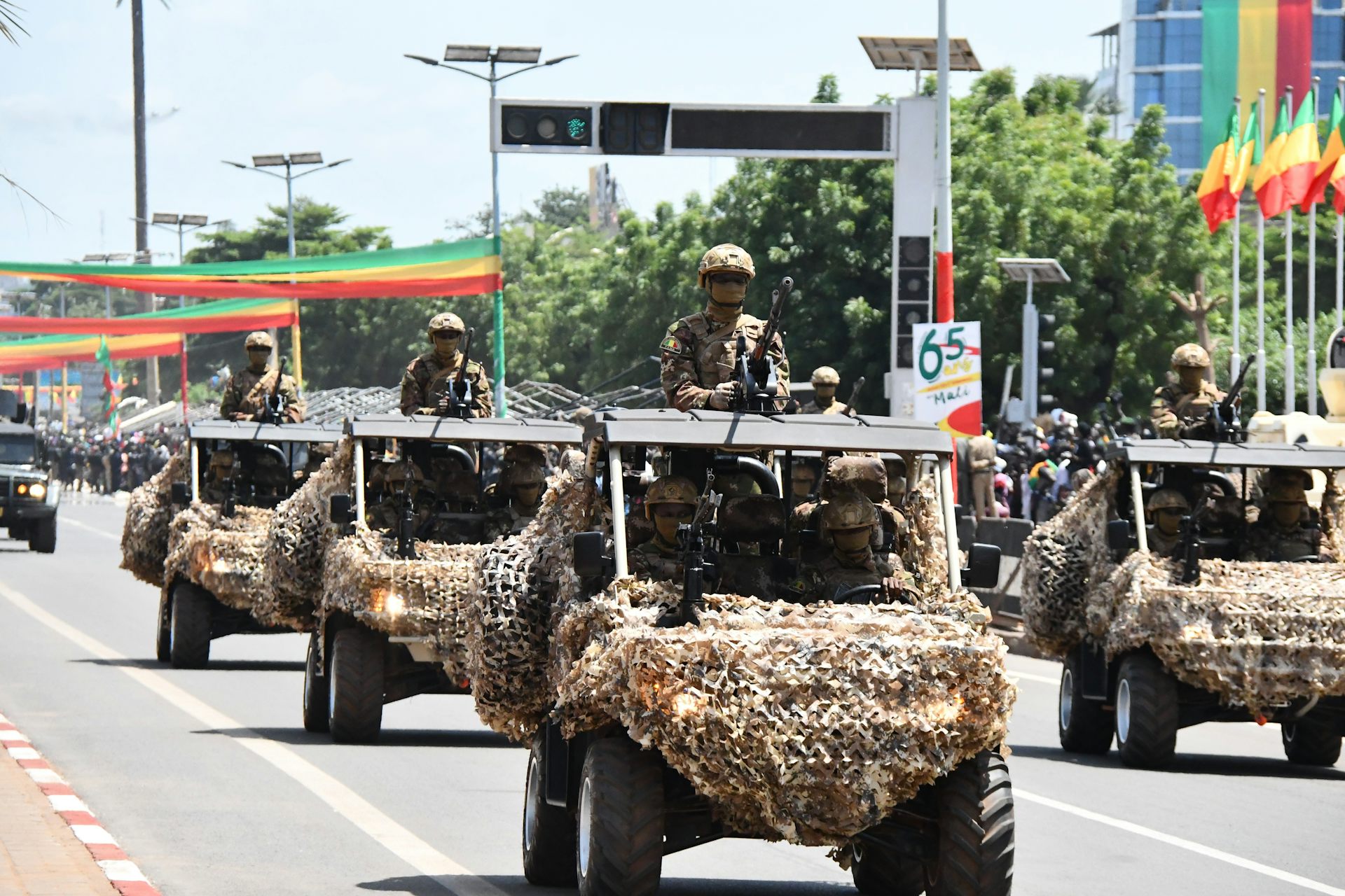 Military vehicles in a street decorated with flags and posters