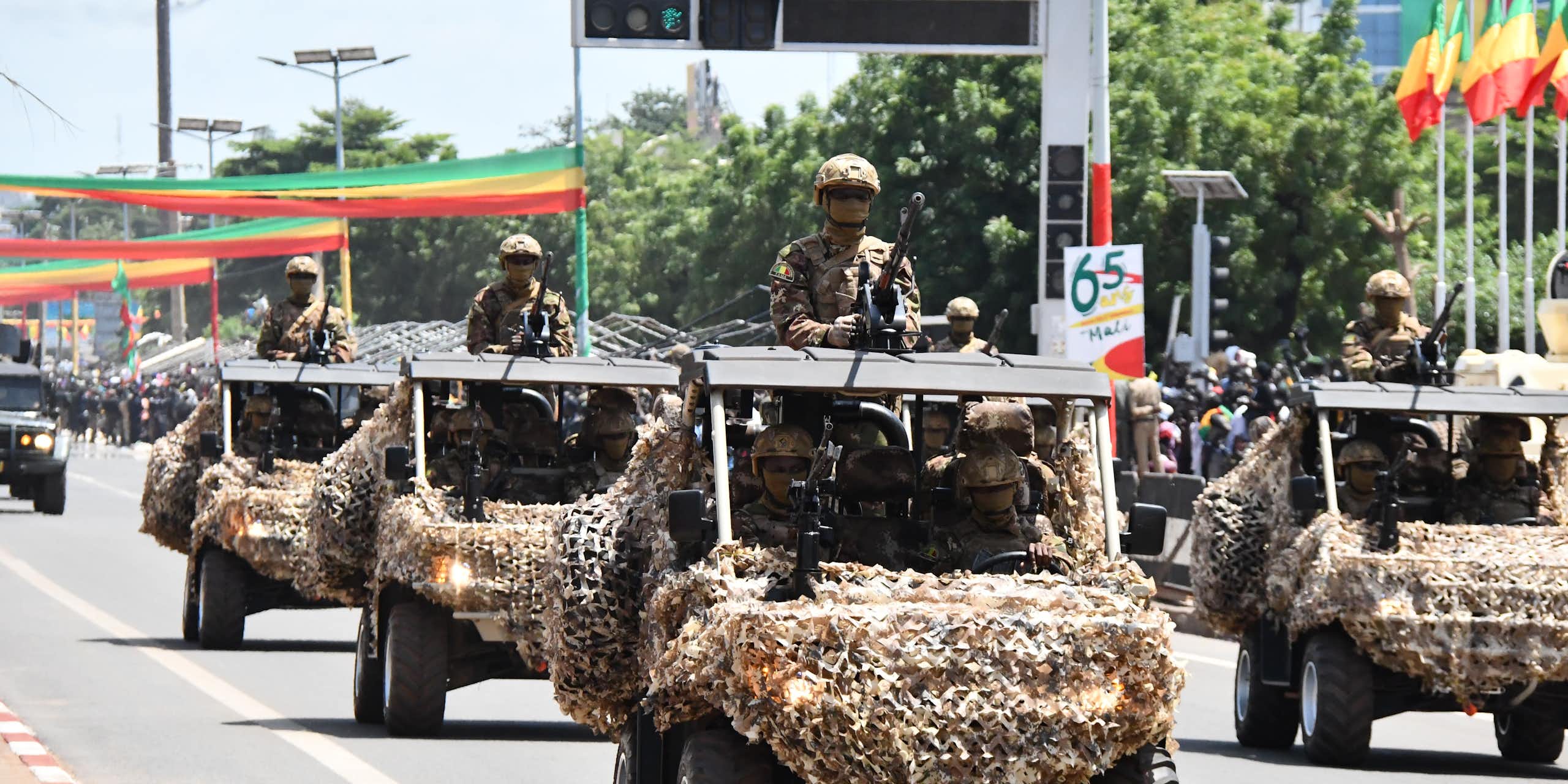 Military vehicles in a street decorated with flags and posters