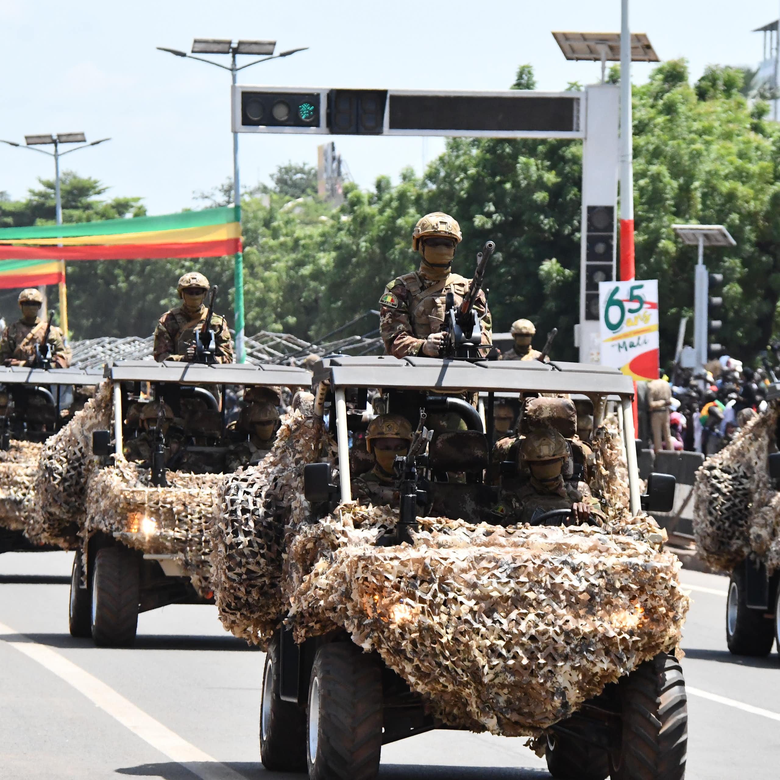 Military vehicles in a street decorated with flags and posters