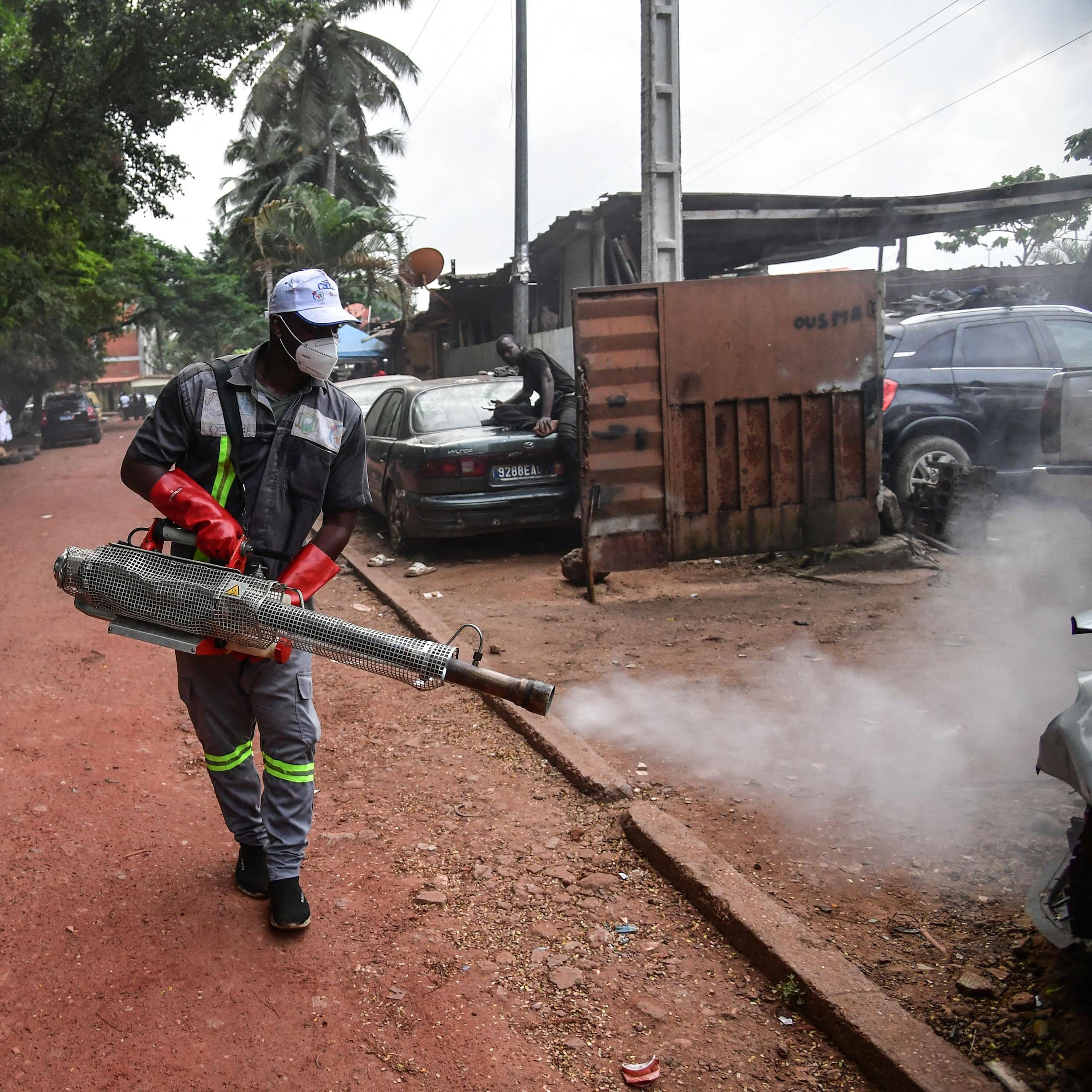 People in protective clothing and masks spray a smoky substance on the street