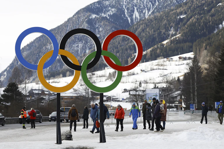 Des personnes marchent près des anneaux olympiques