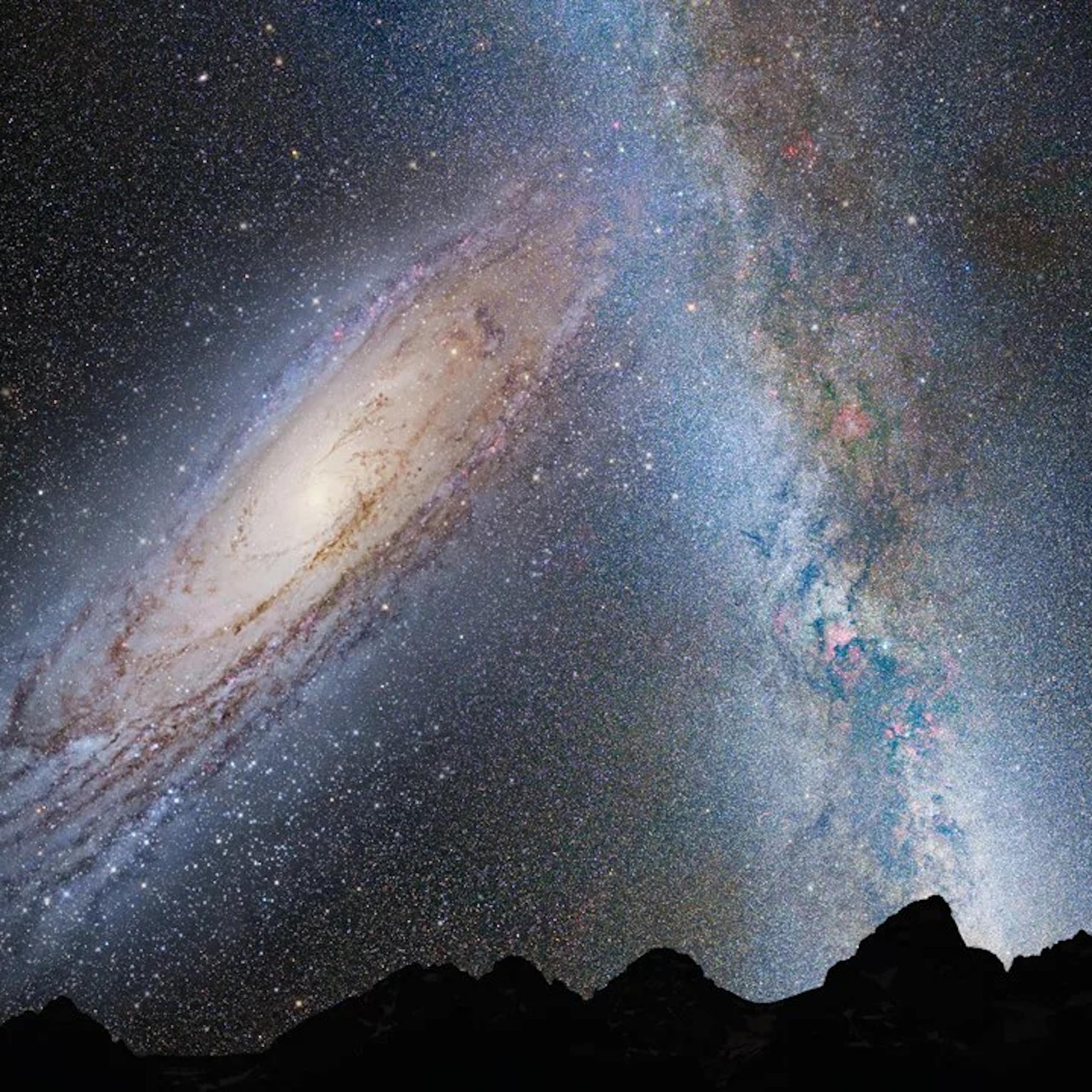 A spiral galaxy shown in the sky against the Milky Way, above a mountain range.
