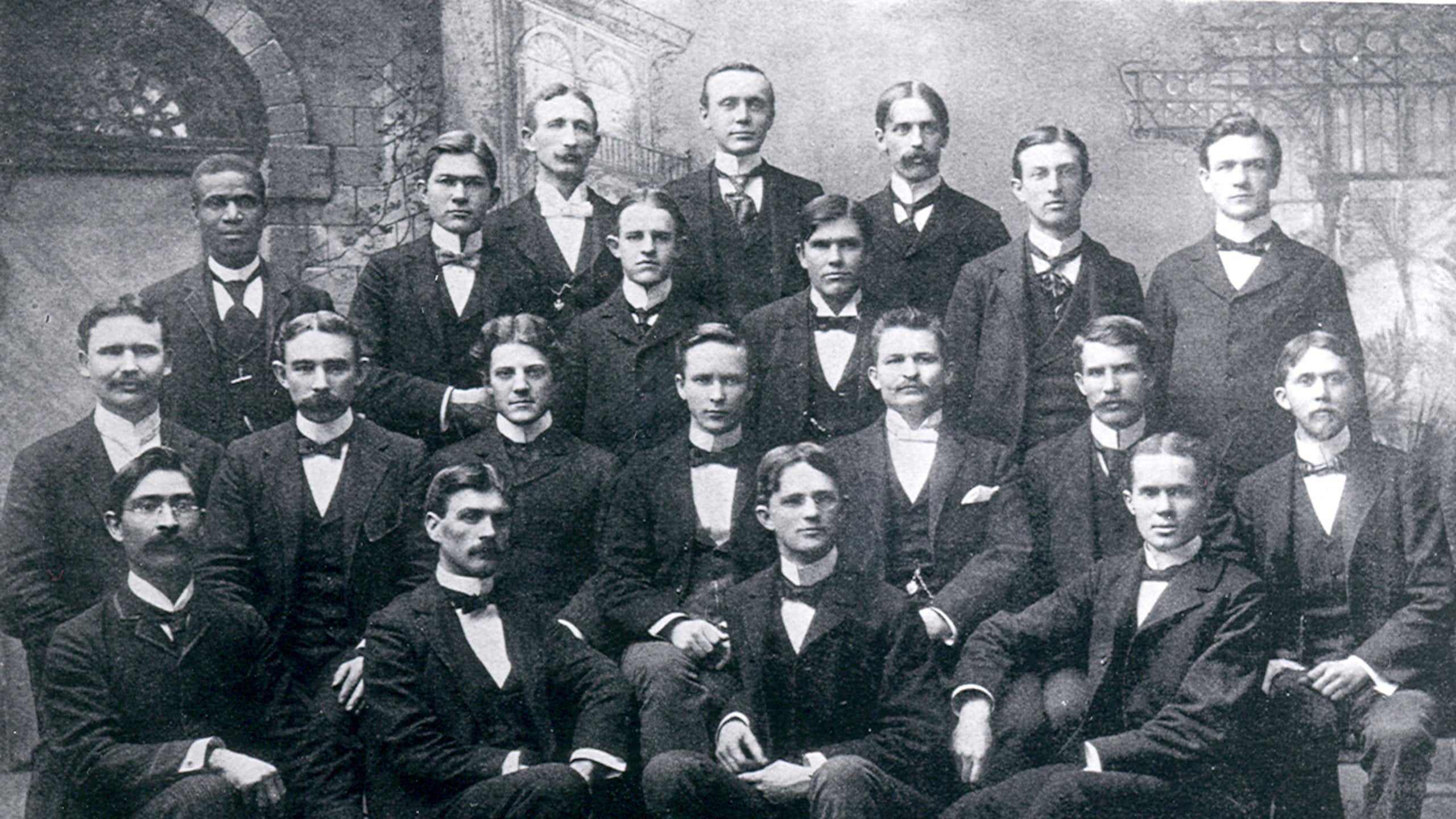 Twenty men are pictured together in a black and white photo.