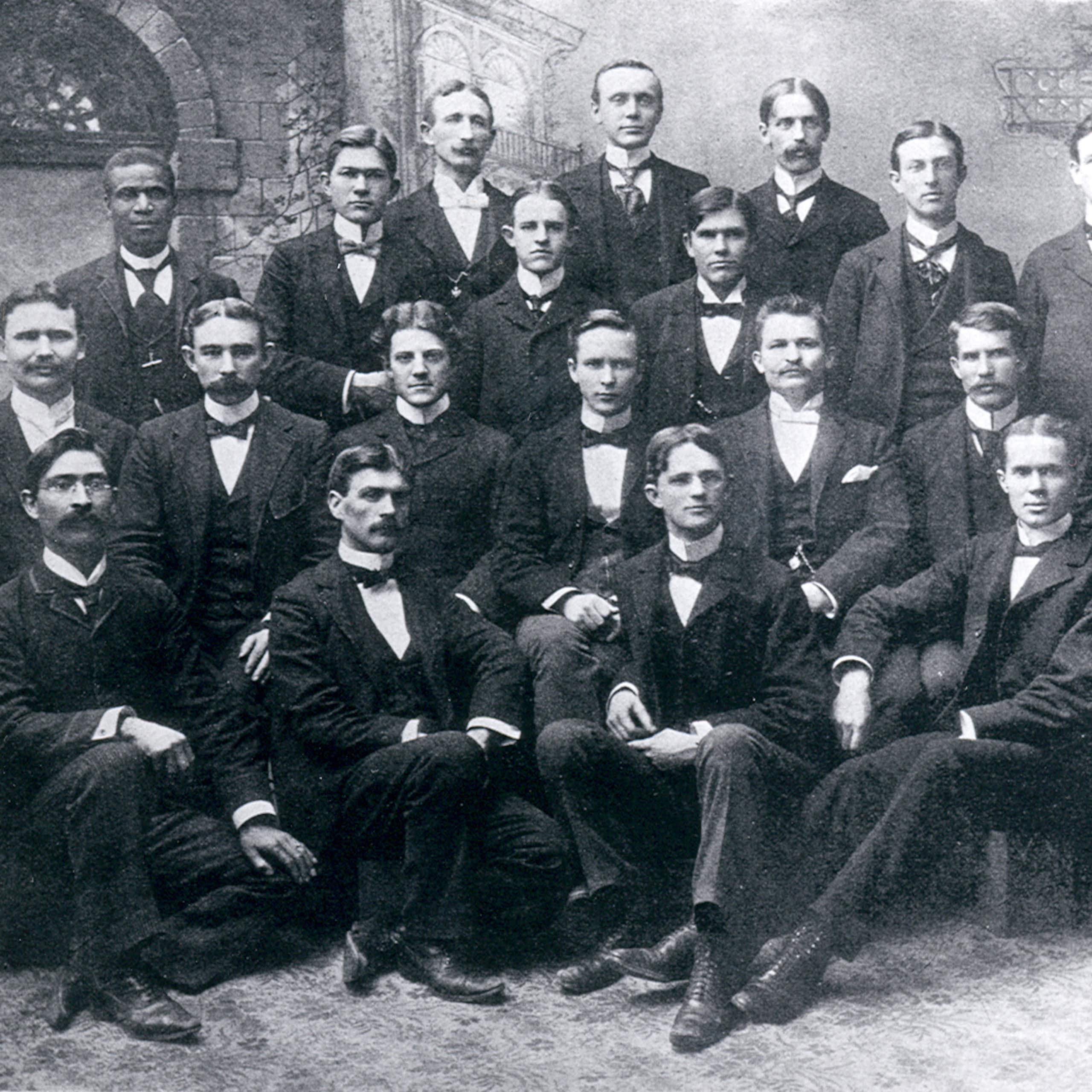 Twenty men are pictured together in a black and white photo.
