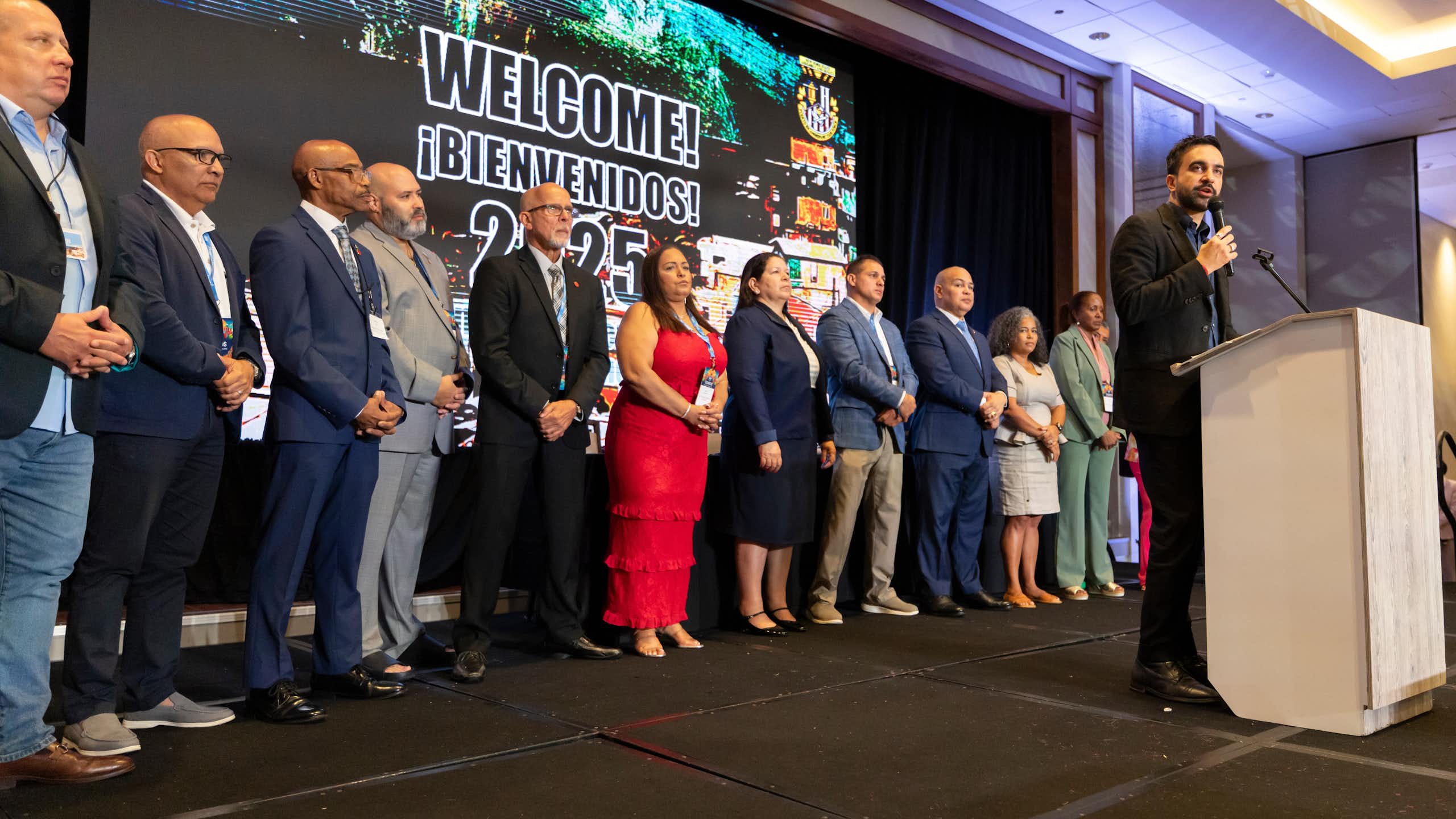 A man in front of a podium speaks to a crowd.