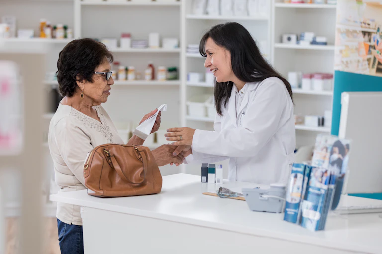 A pharmacist speaks with an older customer about her prescription.