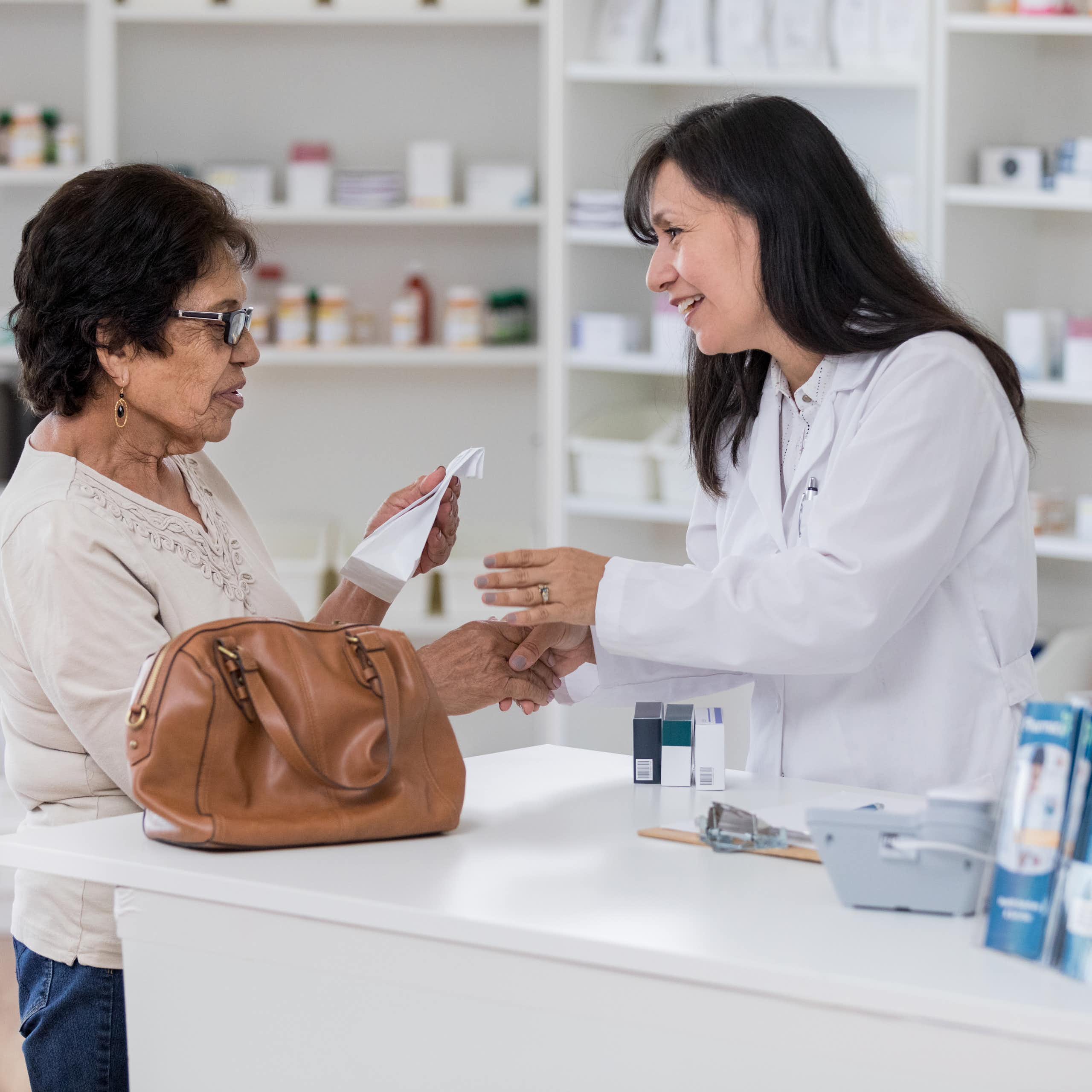 A pharmacist speaks with an older customer about her prescription.