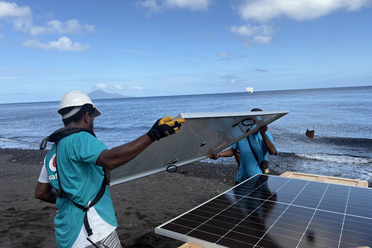 workers unloading solar panels on pacific island.