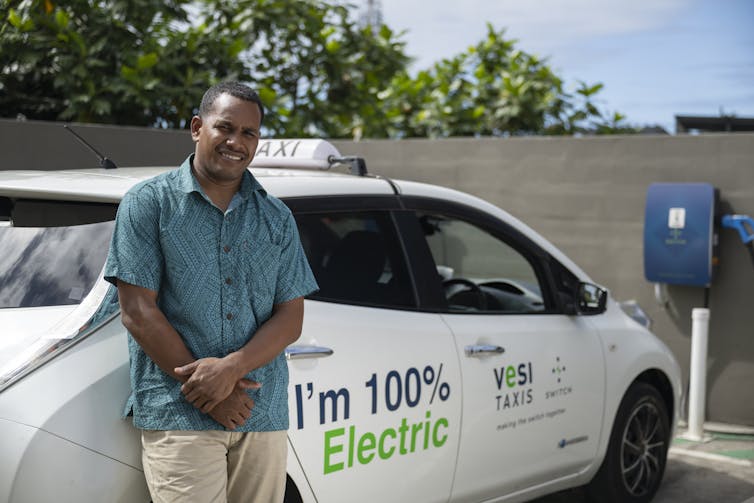 man standing in front of electric taxi.
