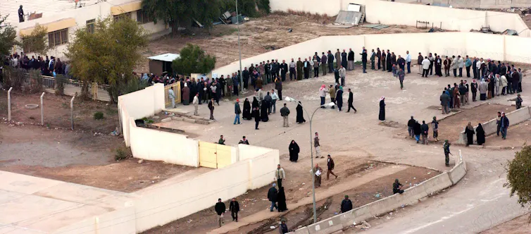 Hundreds of voters line up outside a polling place in Baghdad, Iraq.