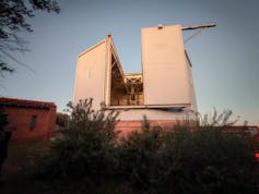 A square shaped two storey building in an outdoor bushy area