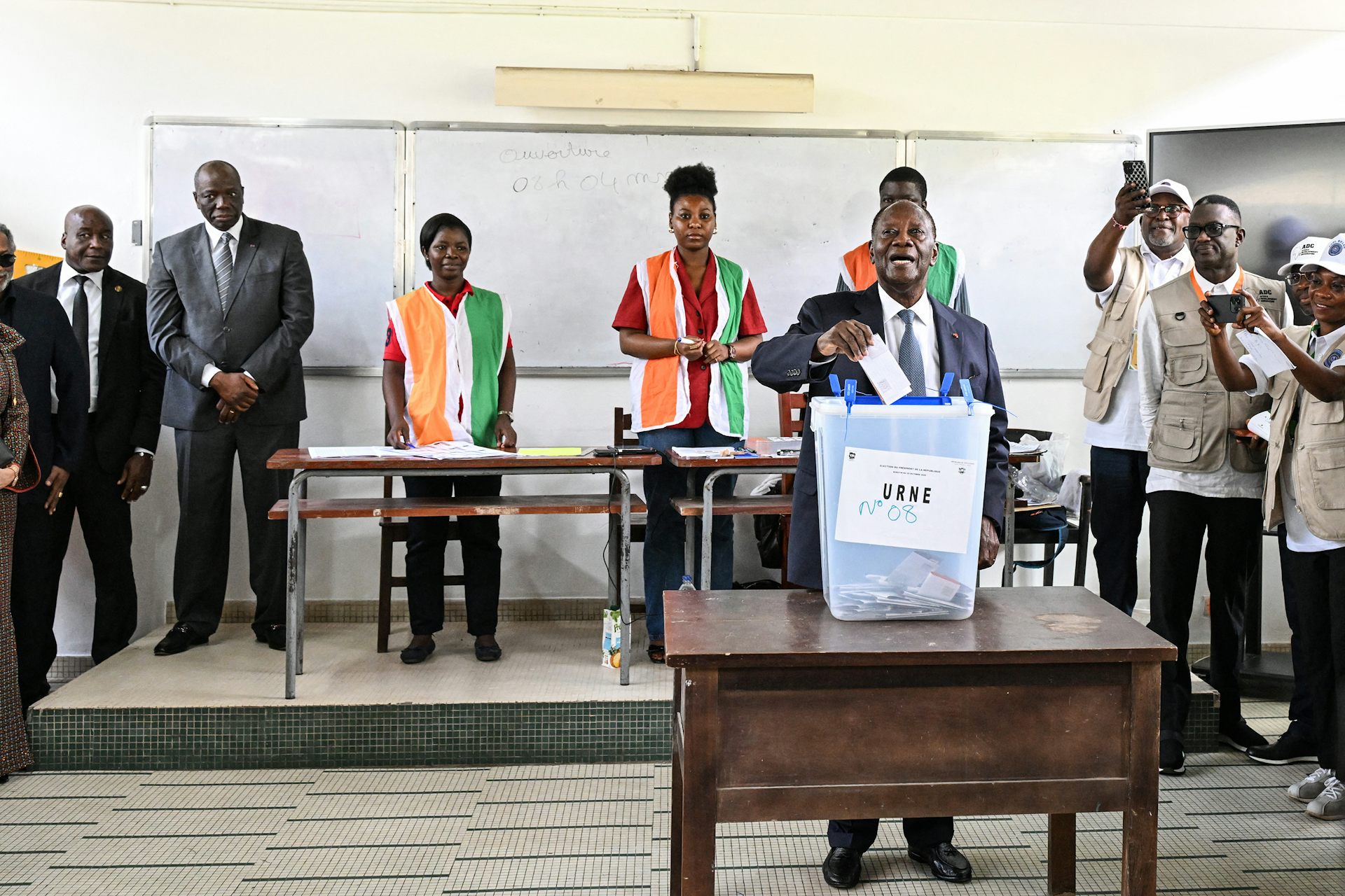 A man wearing white shirt and grey suit casting his ballot 