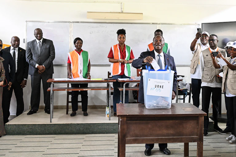A man wearing white shirt and grey suit casting his ballot