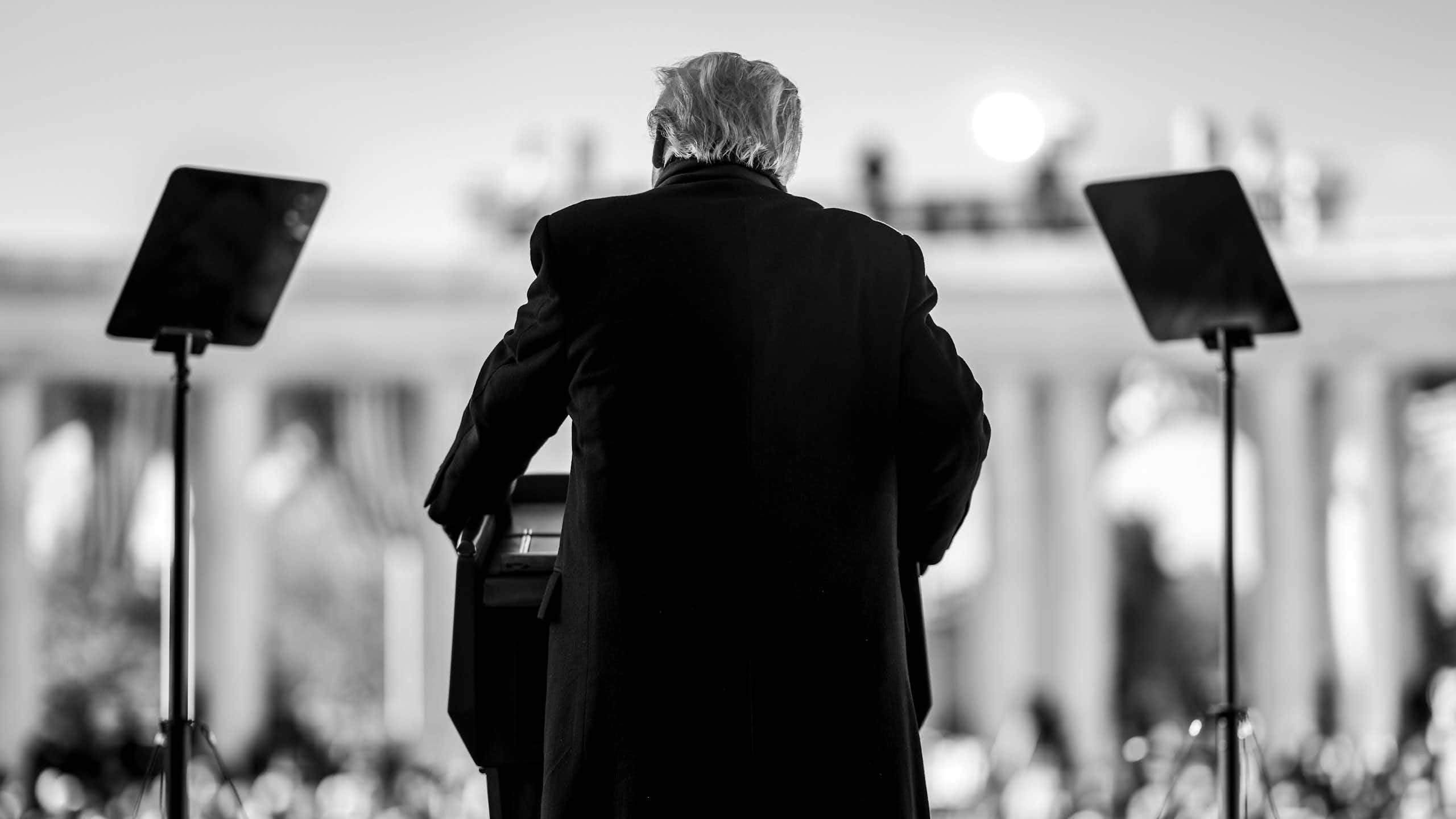 A black and white image of Donald Trump, taken from behind, speaking at the Memorial Amphitheater of Arlington National Cemetery to mark Veterans Day in the US.