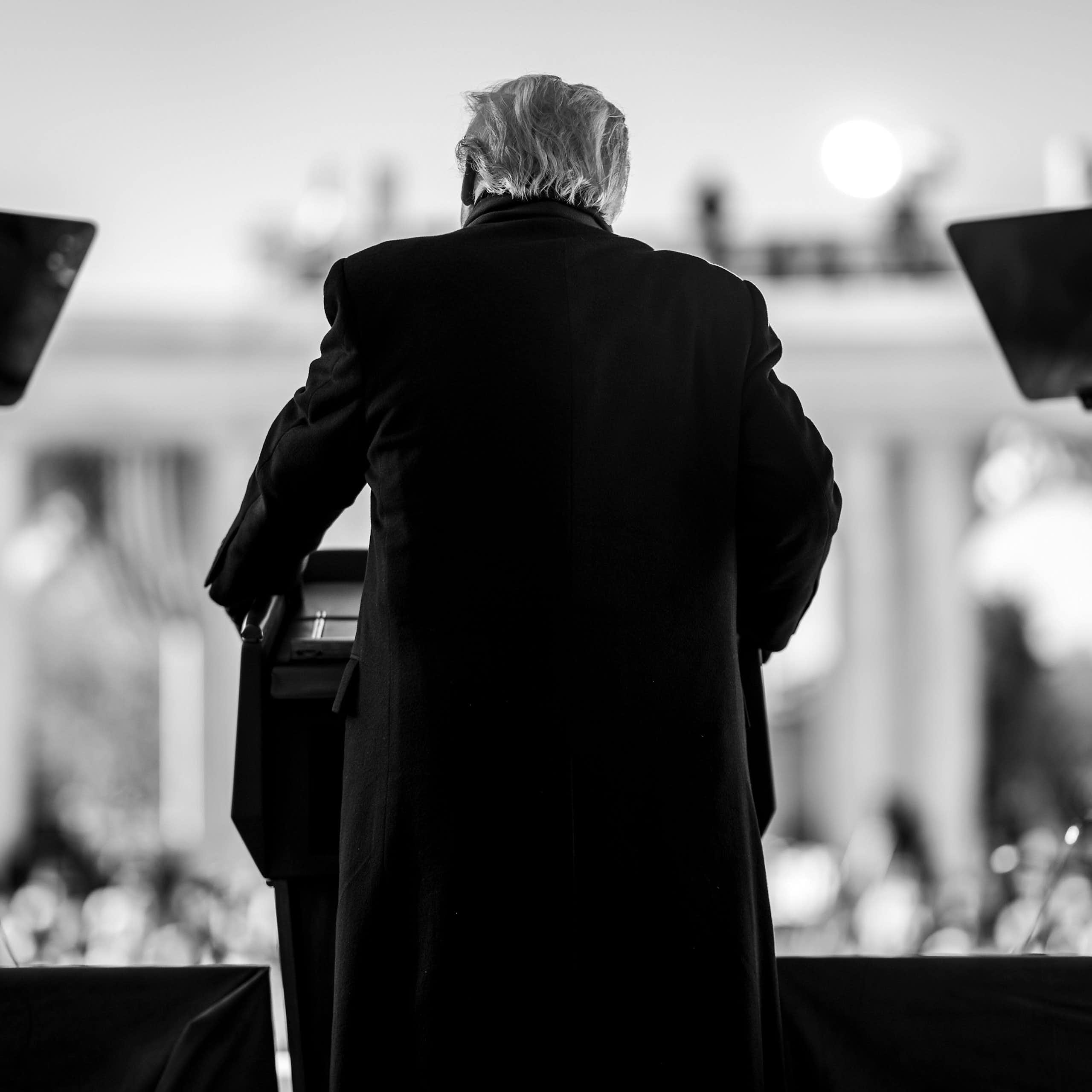 A black and white image of Donald Trump, taken from behind, speaking at the Memorial Amphitheater of Arlington National Cemetery to mark Veterans Day in the US.