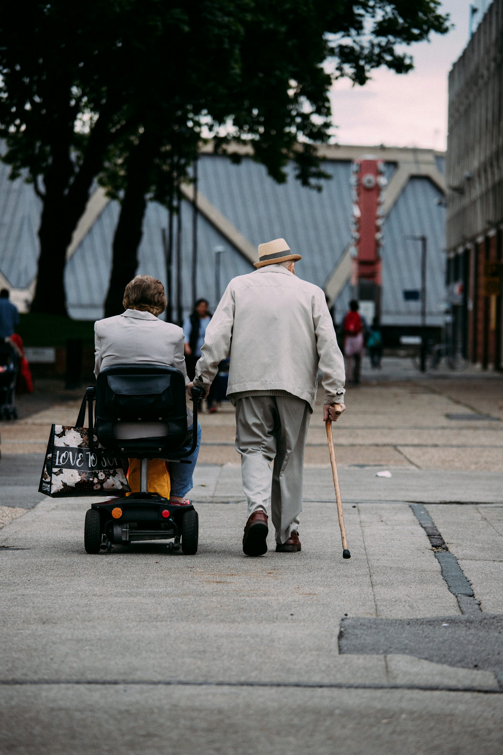 Un homme marche avec une canne tandis qu’une femme se déplace à ses côté en quadriporteur