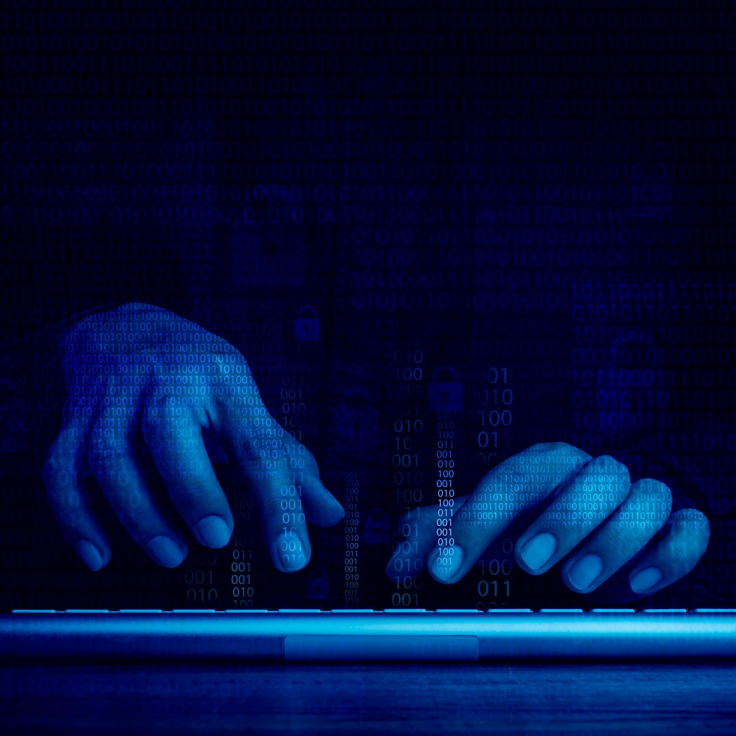 A close up of a pair of hands, lit in blue on a keyboard.