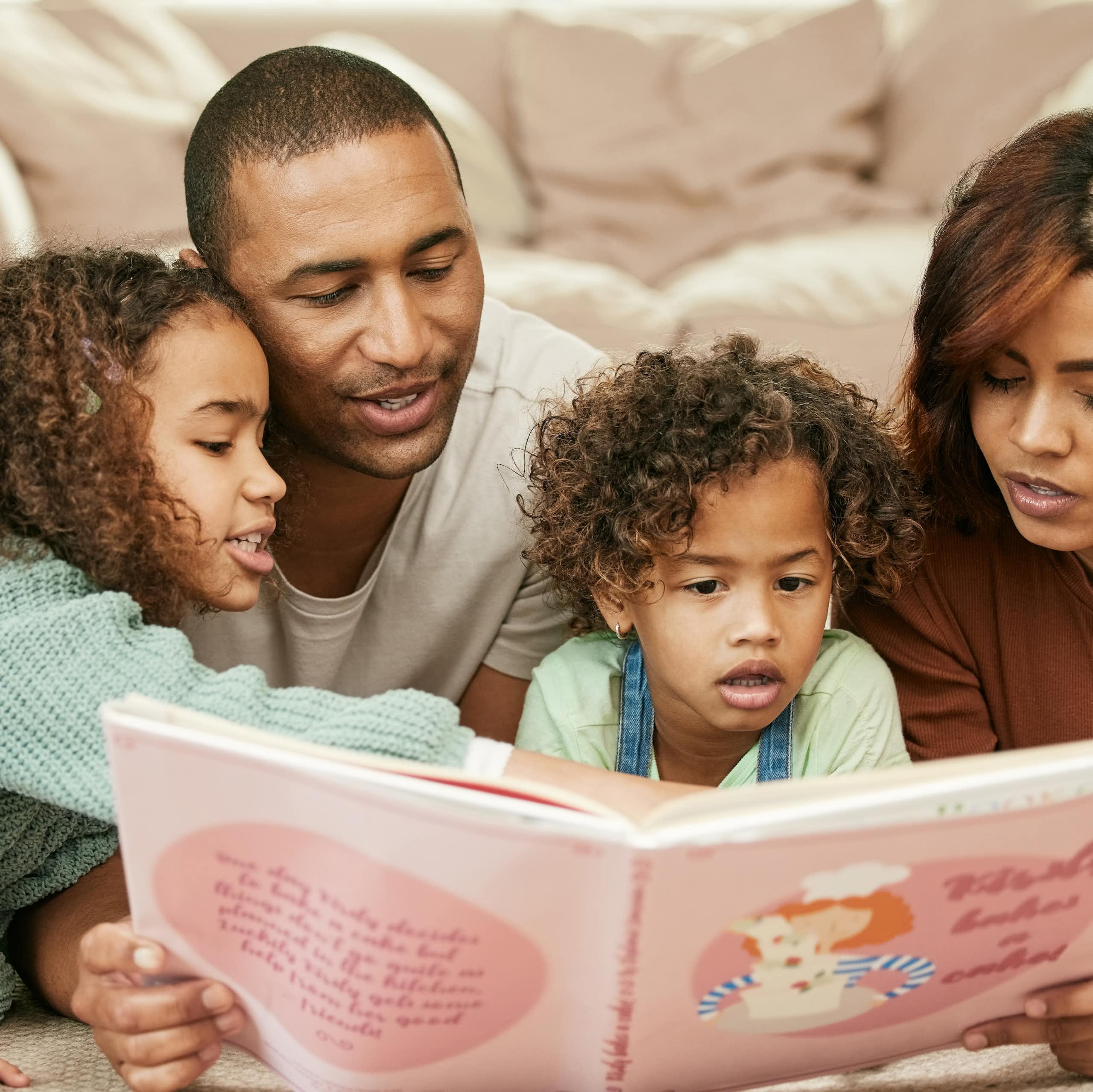Una familia (padre, madre y dos niñas) lee un libro.