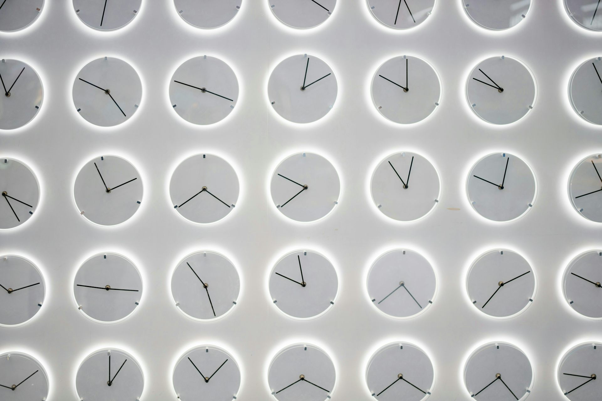 rows of monochromatic gray clocks showing different times