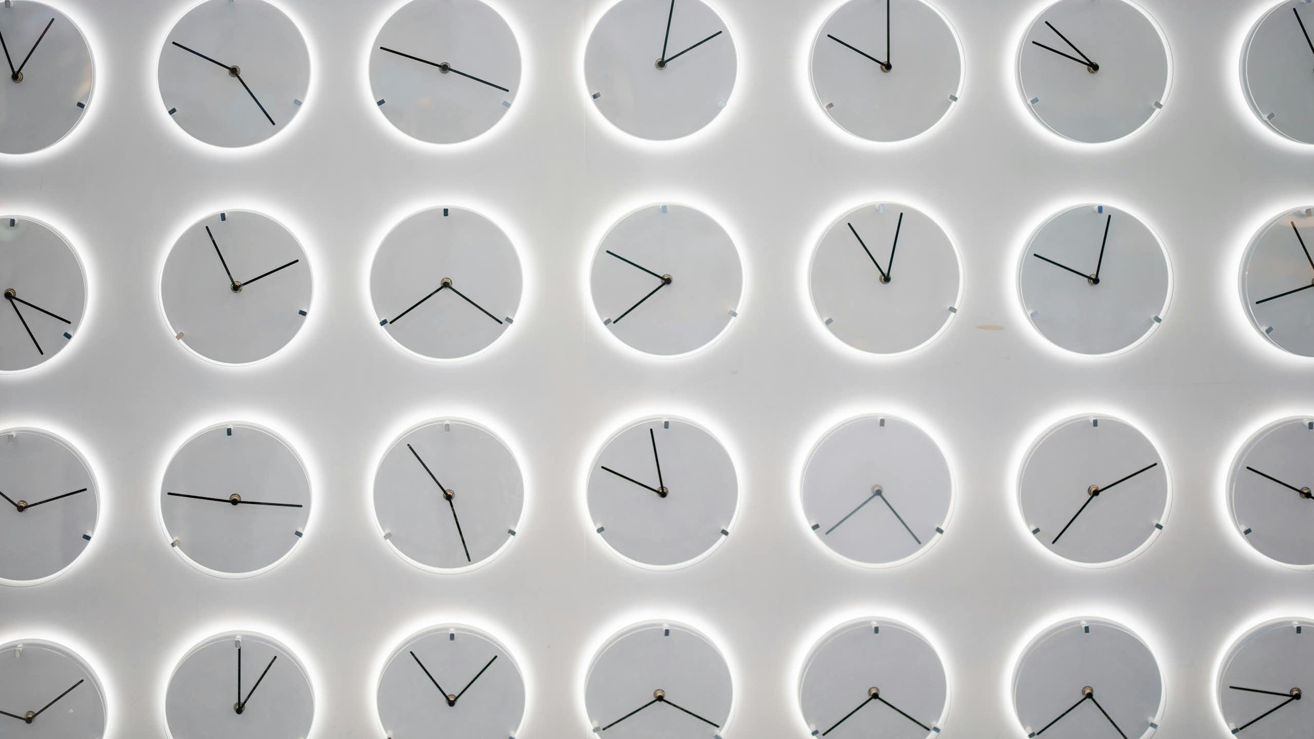 rows of monochromatic gray clocks showing different times