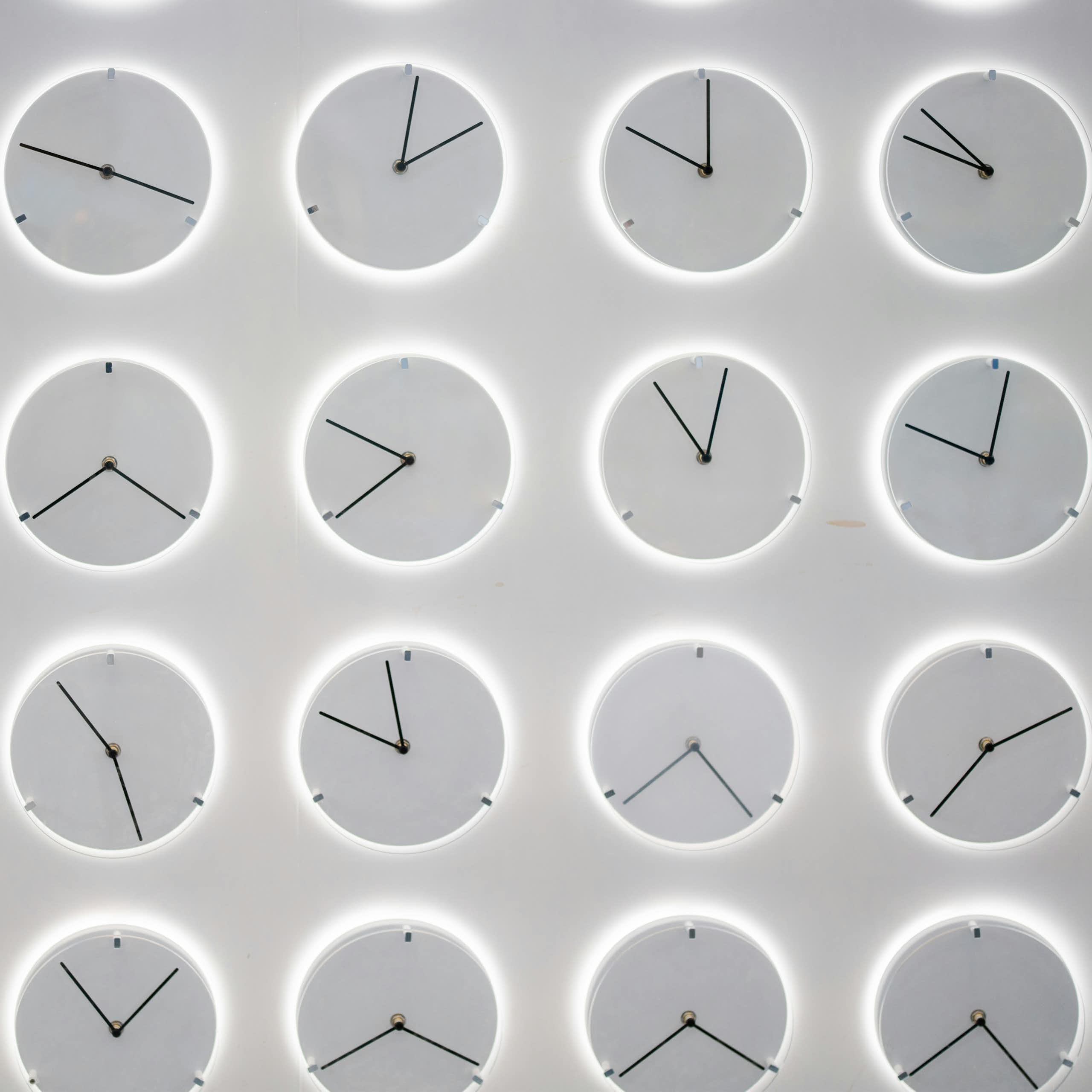 rows of monochromatic gray clocks showing different times