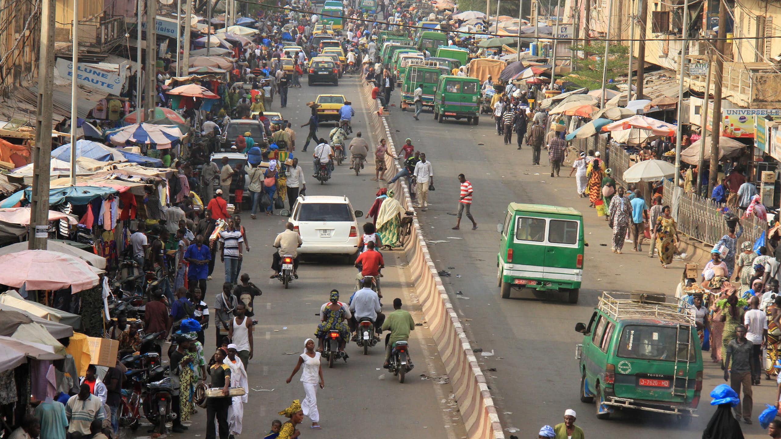 People and cars move along a busy roadway