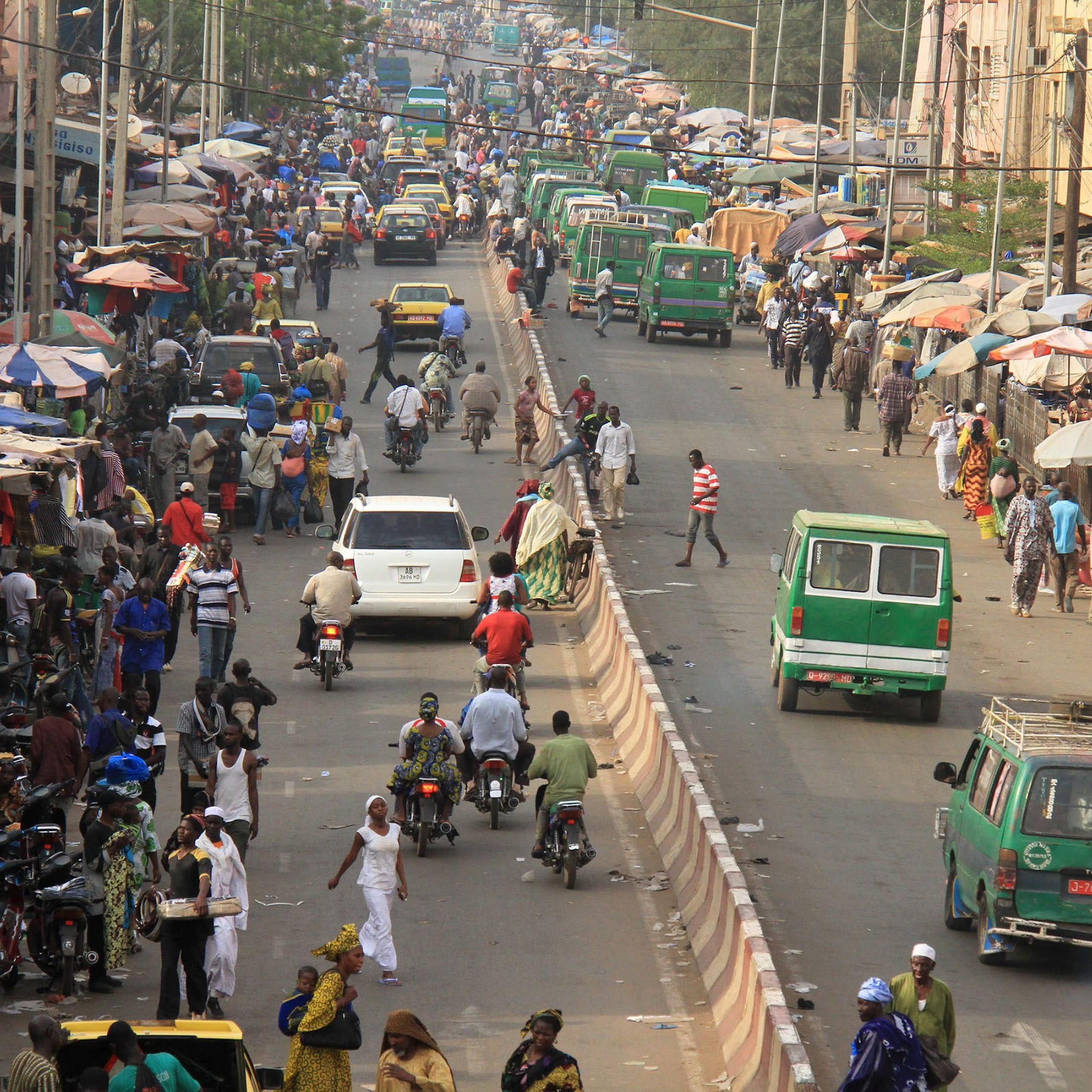 People and cars move along a busy roadway