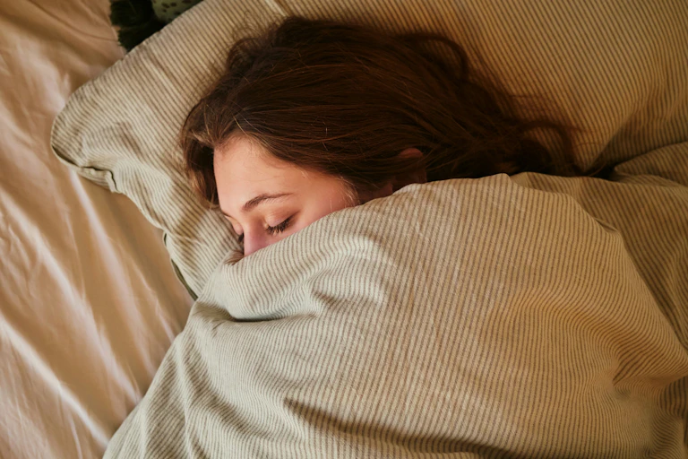 Une personne endormie et blottie dans son lit.