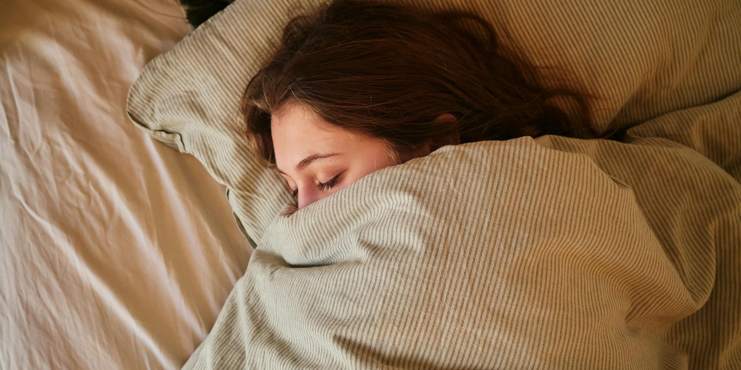 Une personne endormie et blottie dans son lit.