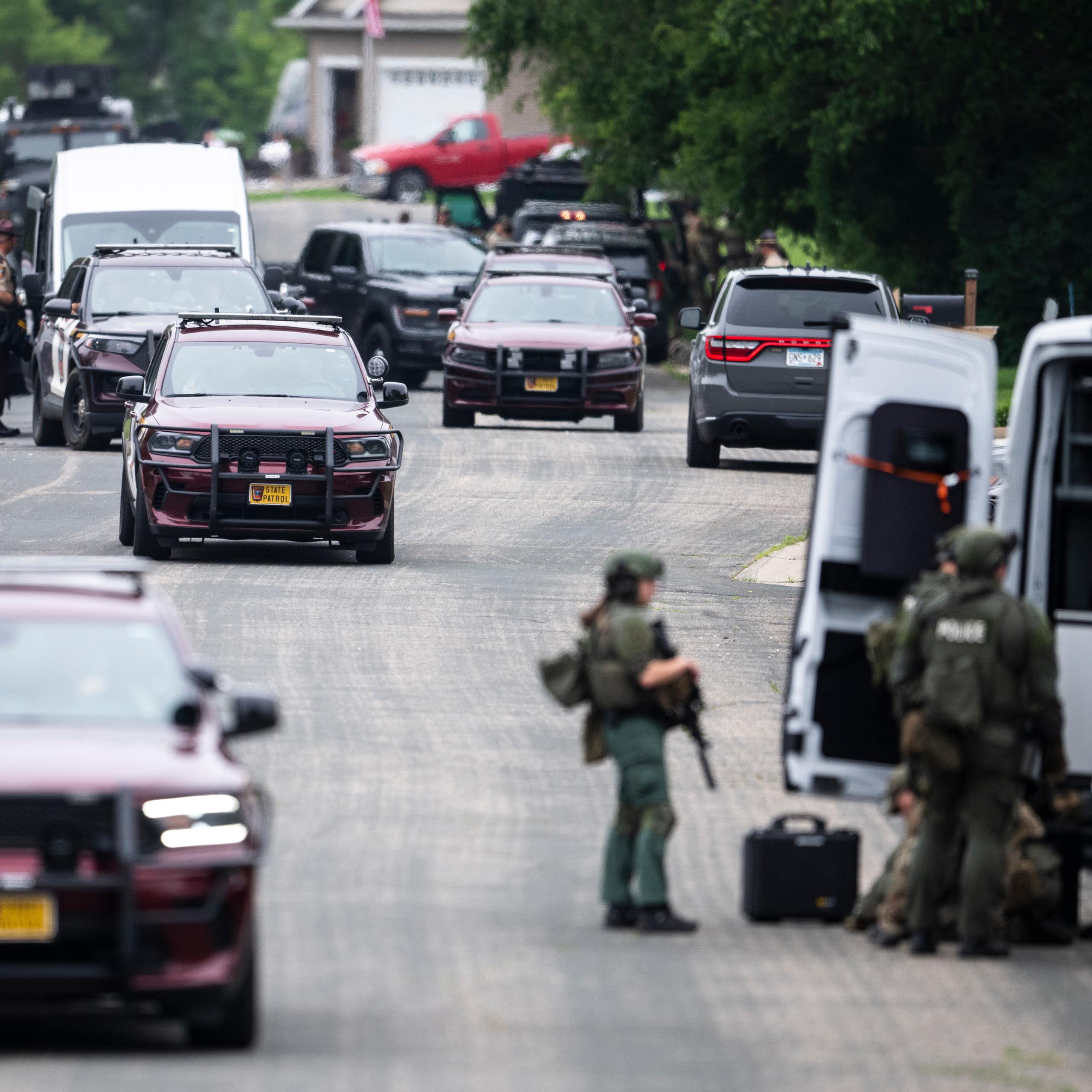 Police vehicles and other cars on a street.