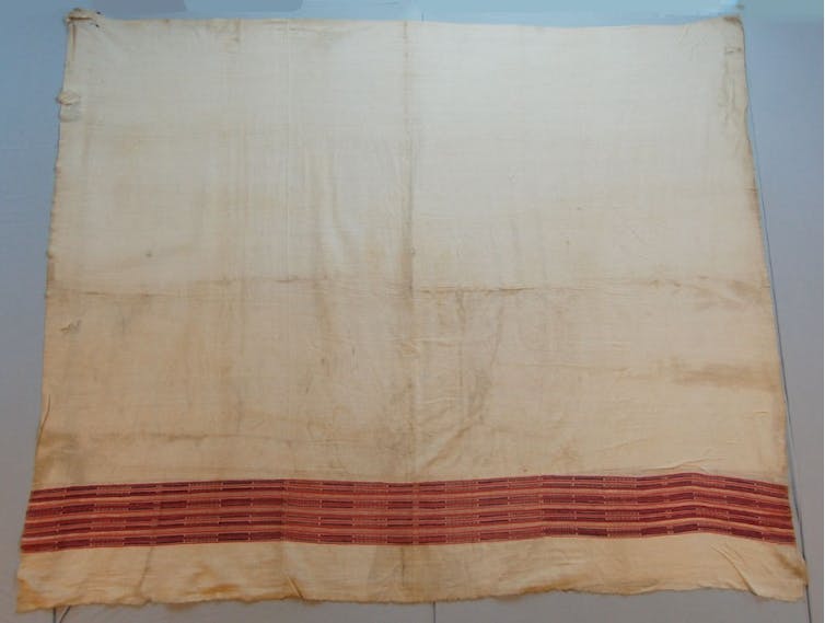 A square piece beige of fabric with red lines running along the bottom end.