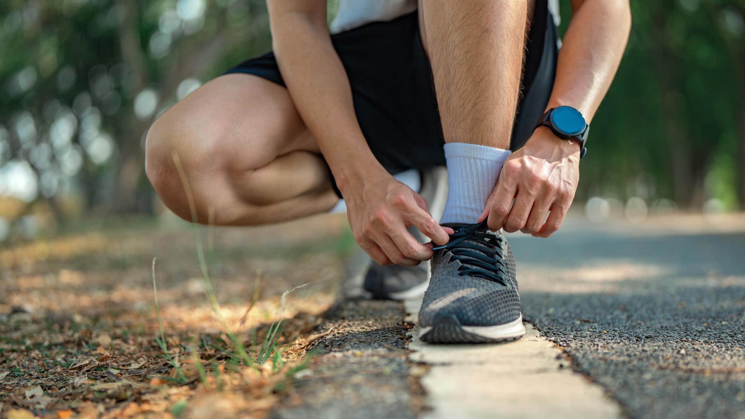 Un corredor se ata los cordones de sus zapatillas.