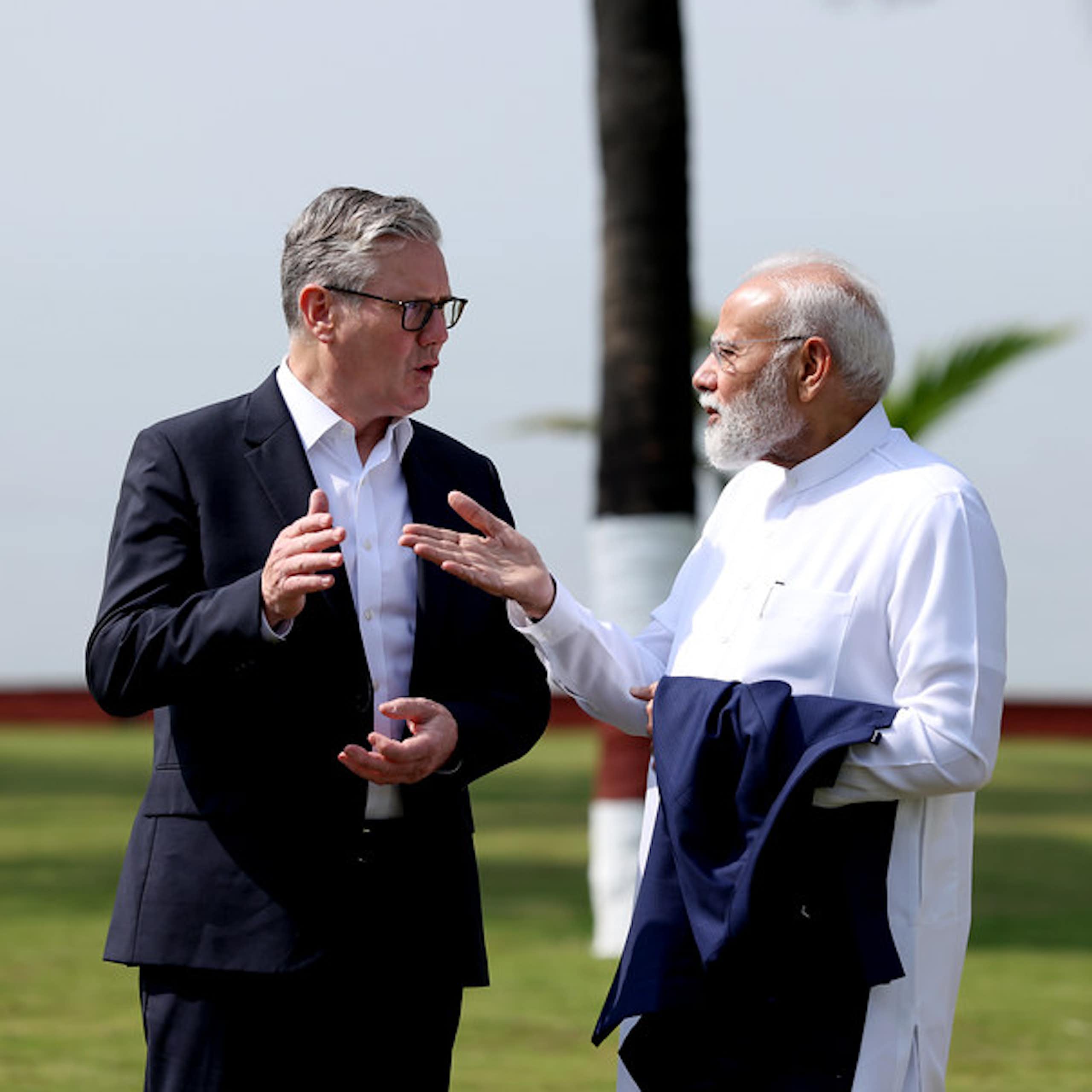 Starmer and Modi chatting outdoors with palm trees in the background