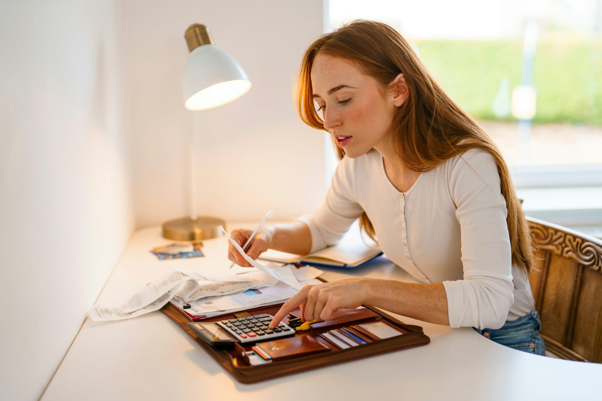 Una mujer hace cuentas con recibos, tarjetas y una calculadora