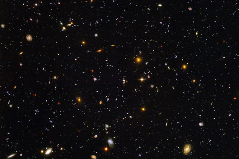 Photo du ciel : sur le fond noir de l'espace, de nombreuses galaxies apparaissent, de différentes tailles et de différentes couleurs.