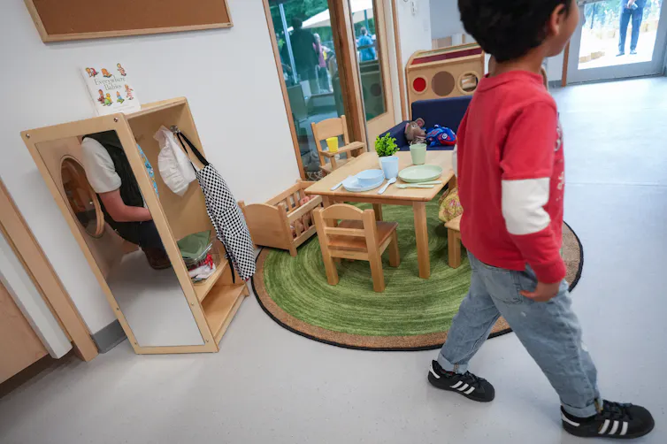 Un niño pasa junto a pequeños muebles para niños en una guardería.