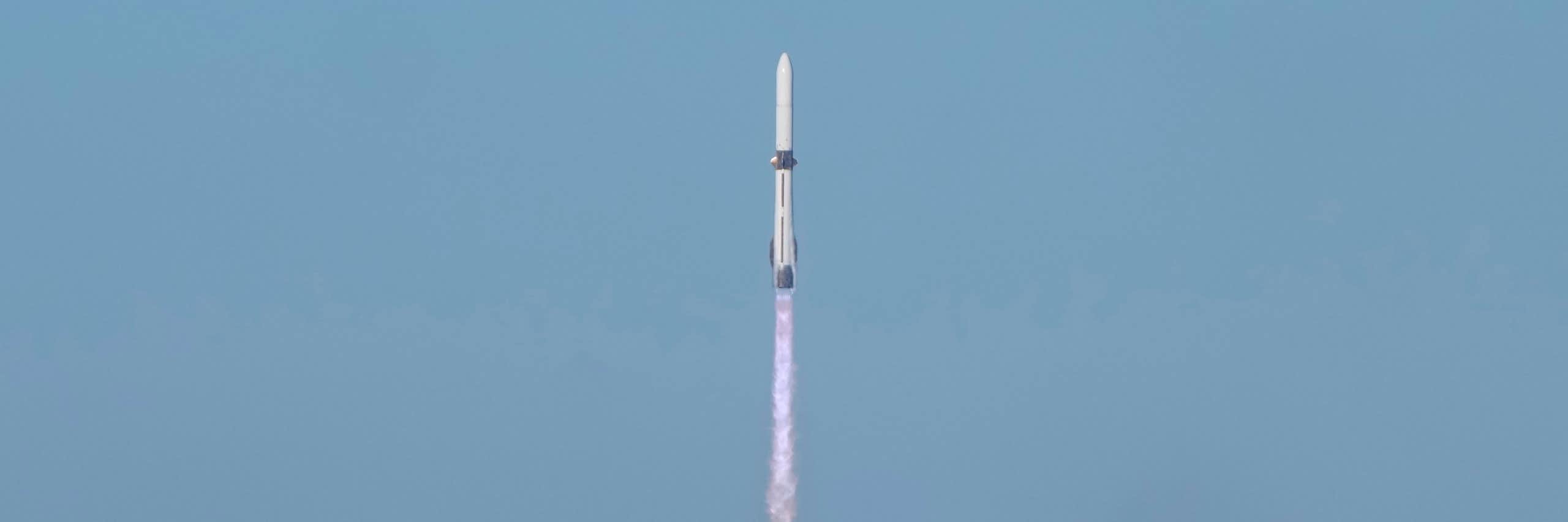 A long, thin rocket lifting off from a smoke-filled launchpad.