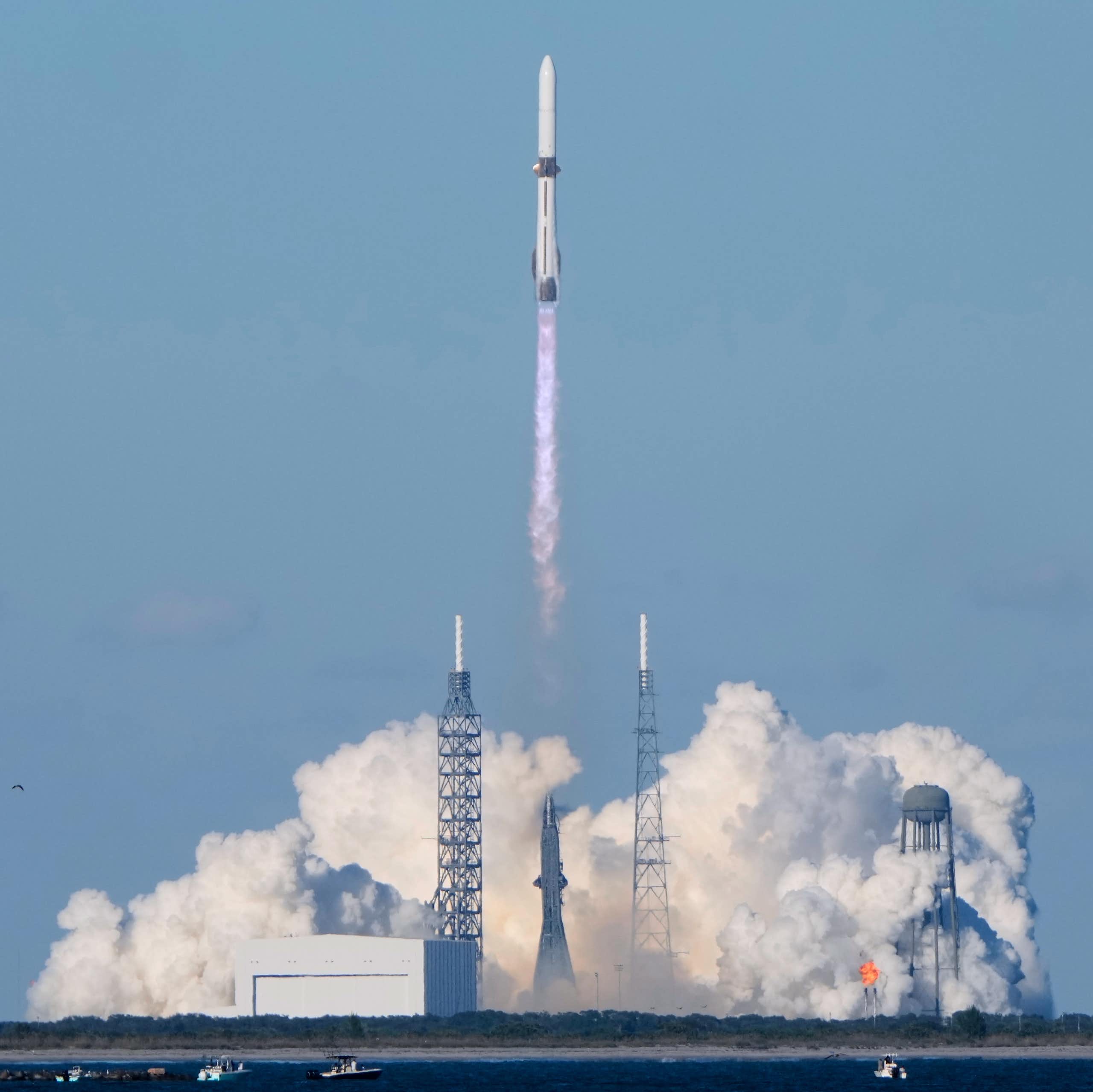 A long, thin rocket lifting off from a smoke-filled launchpad.