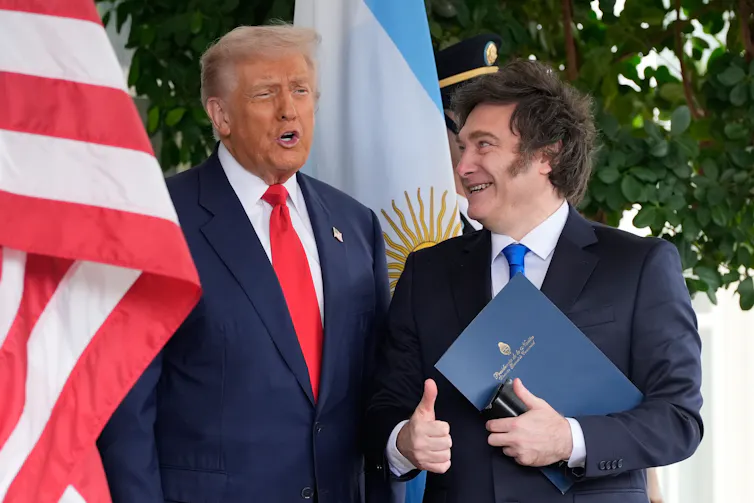 Two men in suits stand next to each other.
