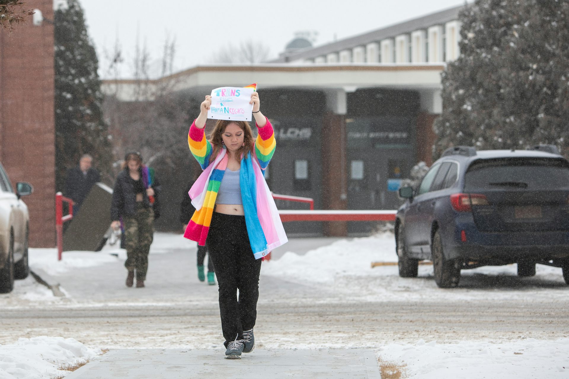 Un estudiante con un abrigo de arcoíris lleva un cartel.