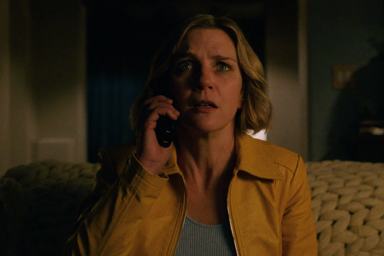 A women with a phone held up to her ear has a fearful expression on her face.