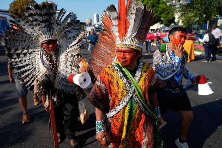 Indigenous protestors wearing large feathered headdresses at the UN30 COP meeting in Belem