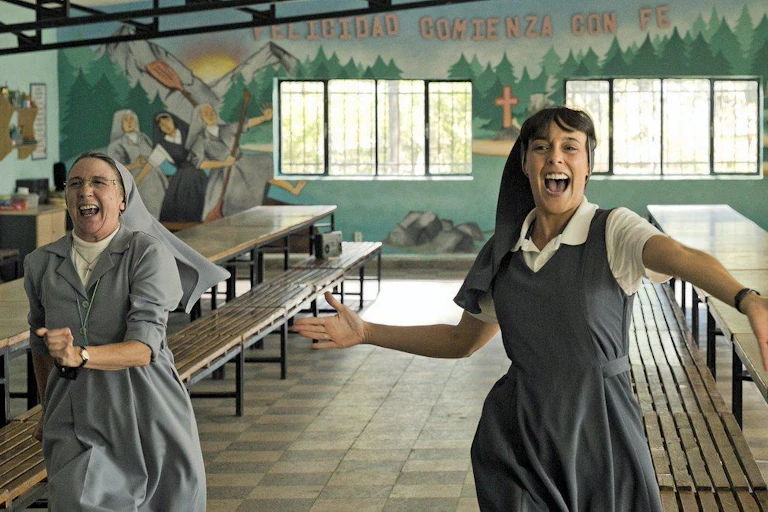 Dos monjas bailan en un comedor vacío.
