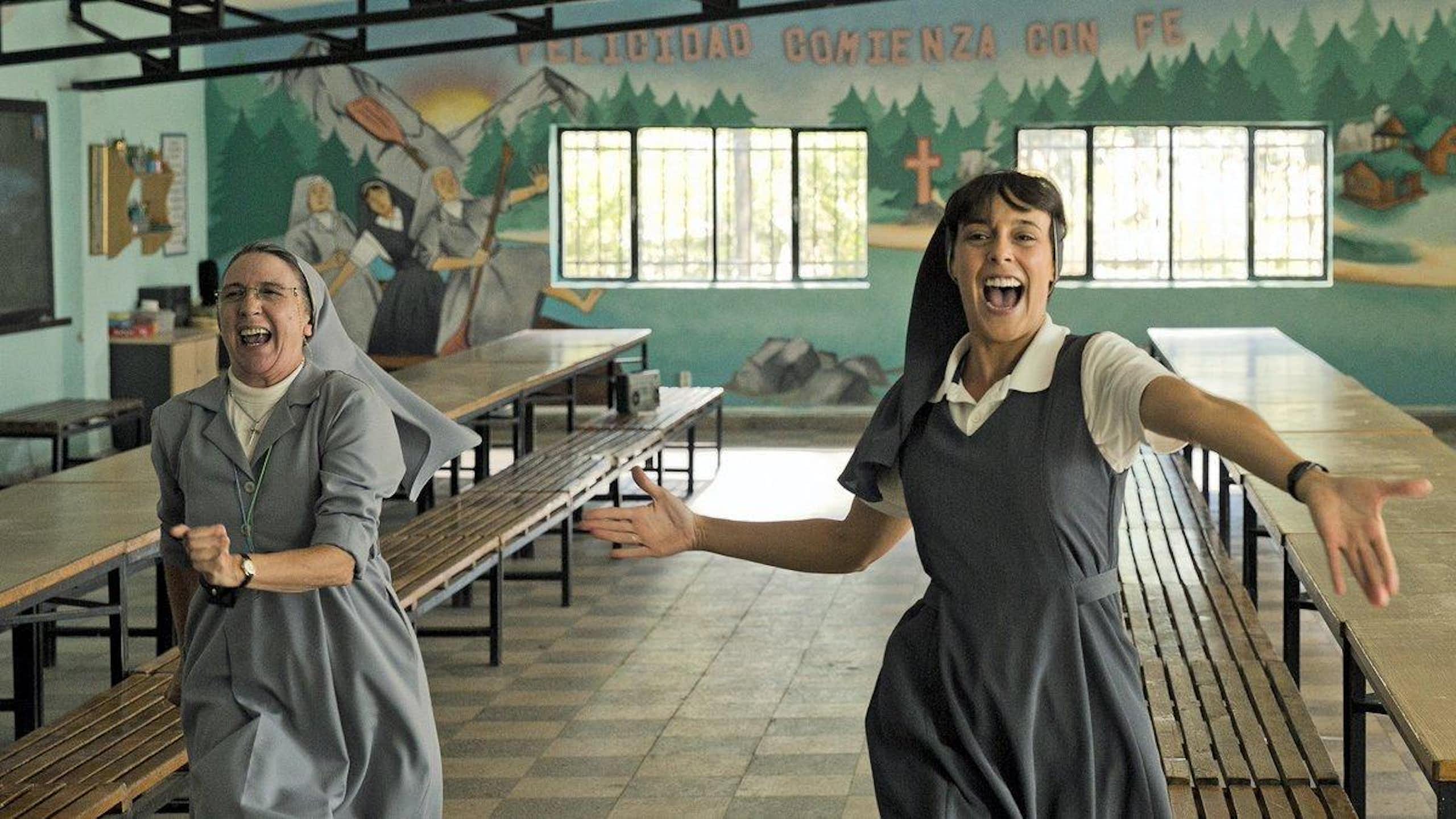 Dos monjas bailan en un comedor vacío.