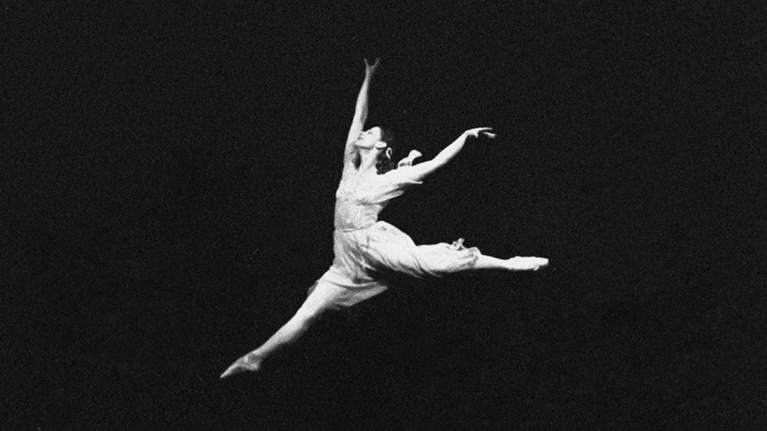 Fotografía de una mujer de blanco saltando y bailando sobre un fondo negro.