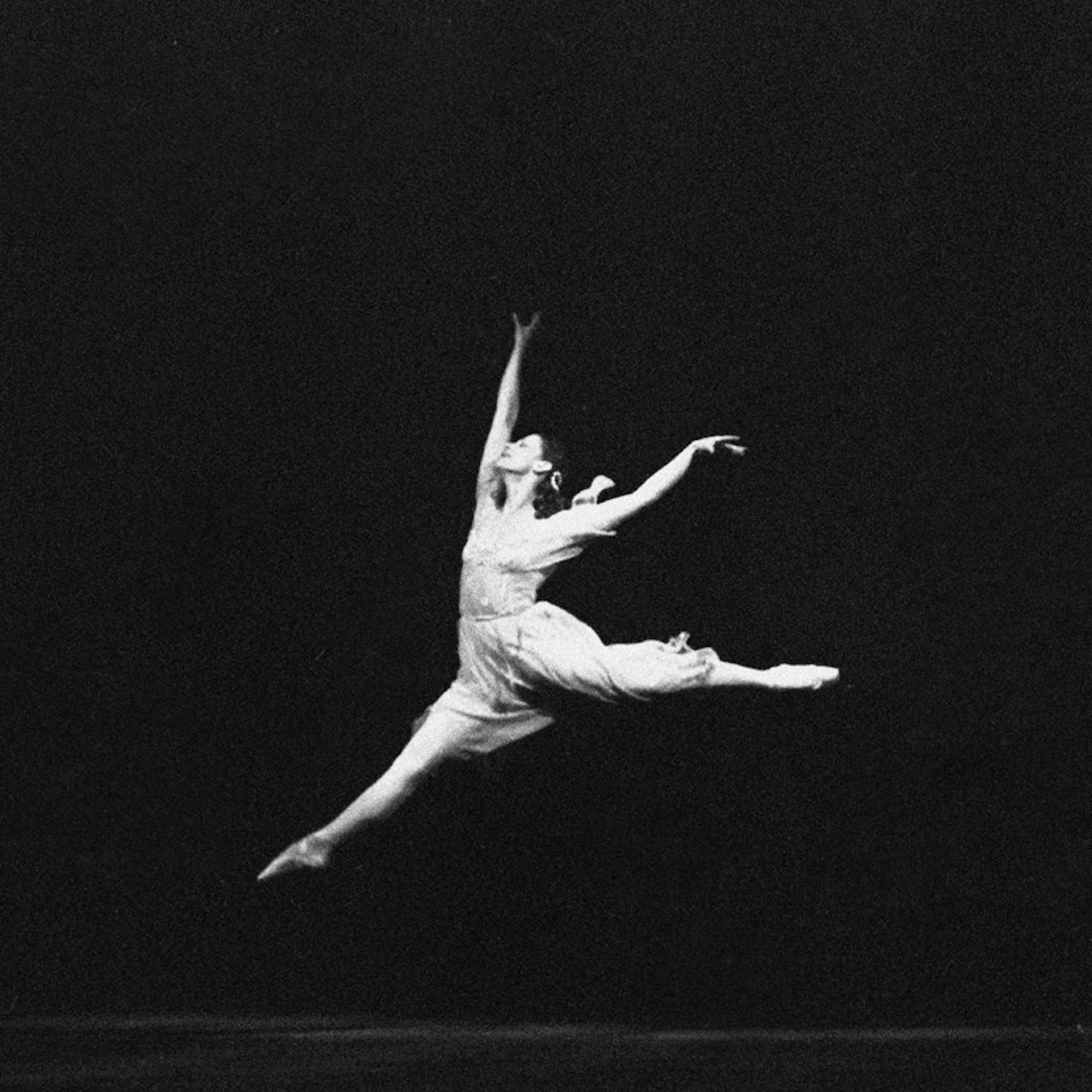 Fotografía de una mujer de blanco saltando y bailando sobre un fondo negro.
